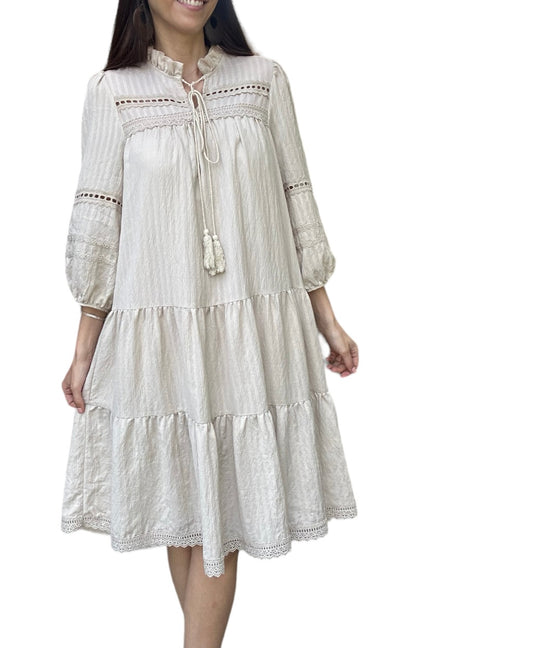 Robe d'été légère Daniella, élégante beige doublée avec des détails en dentelle et des broderies délicates. Cette robe à manches trois-quarts présente une encolure à cordon avec des pompons, ajoutant une touche bohème et décontractée.

La coupe ample et fluide est parfaite pour les journées chaudes, offrant confort et style. La robe est ornée de plusieurs volants, apportant du volume et du mouvement à chaque pas.
