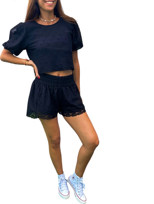 Cet ensemble chic et décontracté comprend un haut court et un short assorti, tous deux confectionnés dans un tissu noir à motif ajouré.
Le haut présente des manches bouffantes pour une touche féminine et élégante, tandis que le short à taille élastique assure un confort optimal. Les finitions en dentelle ajoutent une note délicate et raffinée à l'ensemble.